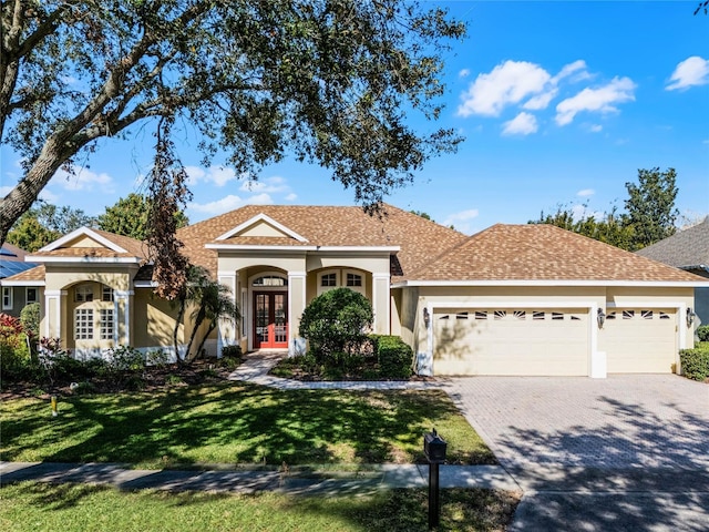 ranch-style home featuring french doors, a front yard, and a garage