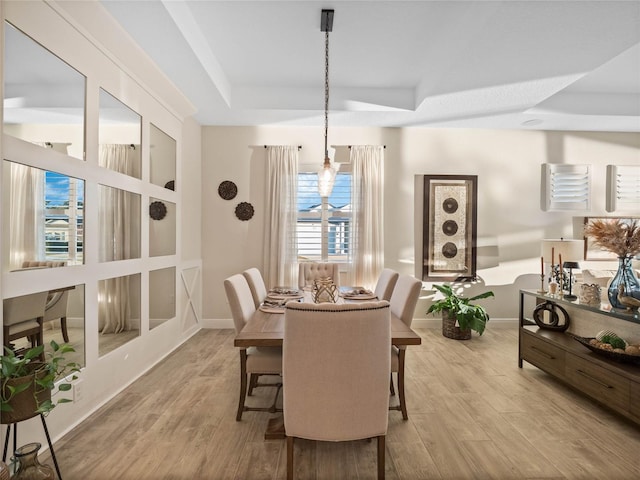 dining area with a tray ceiling and light wood-type flooring