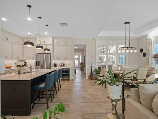 kitchen featuring pendant lighting, a large island, wine cooler, and stainless steel fridge