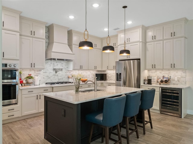 kitchen with appliances with stainless steel finishes, pendant lighting, sink, wine cooler, and custom exhaust hood