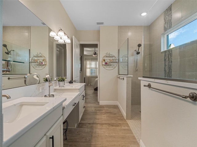 bathroom with ceiling fan, tiled shower, vanity, and hardwood / wood-style floors