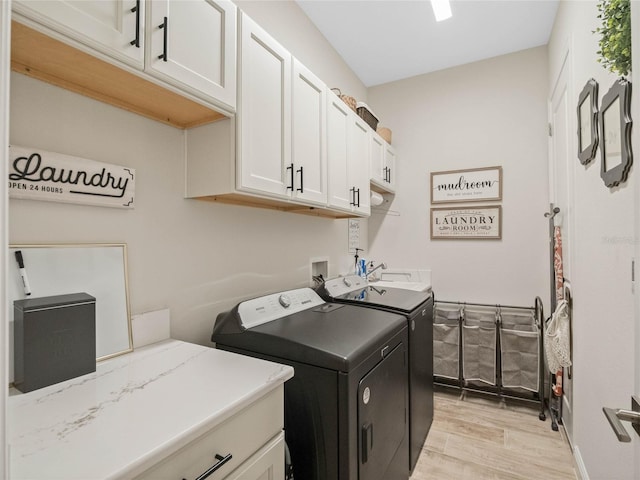 laundry area with cabinets, washer and clothes dryer, and light hardwood / wood-style floors