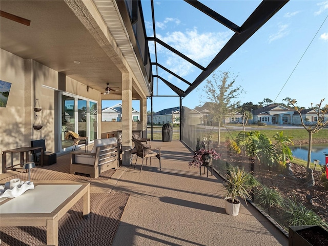 view of patio / terrace with an outdoor living space, a water view, ceiling fan, and a lanai