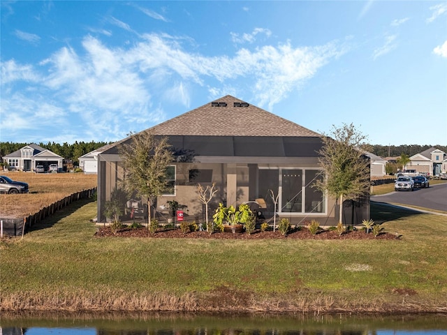 rear view of house with a lawn and a water view