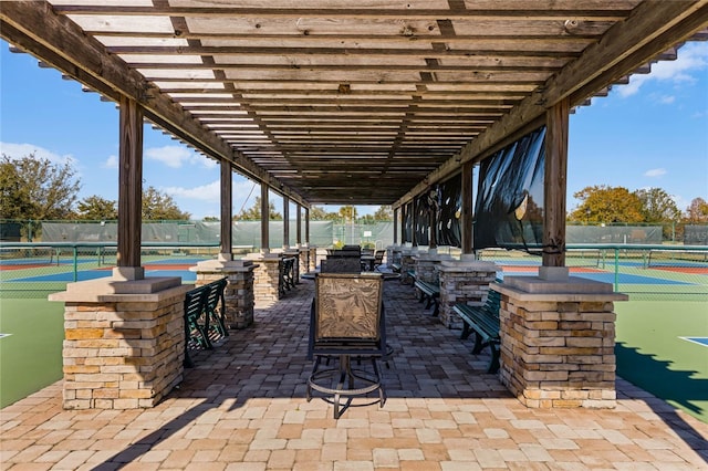 view of patio / terrace featuring a pergola, tennis court, and an outdoor bar