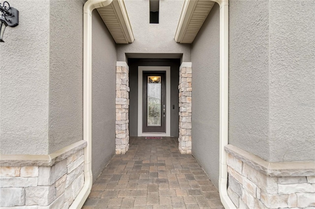 doorway to property featuring stone siding and stucco siding