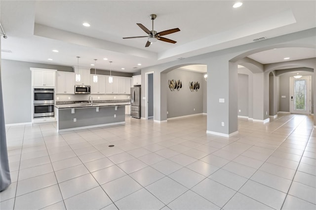 kitchen with appliances with stainless steel finishes, open floor plan, a raised ceiling, and light tile patterned floors