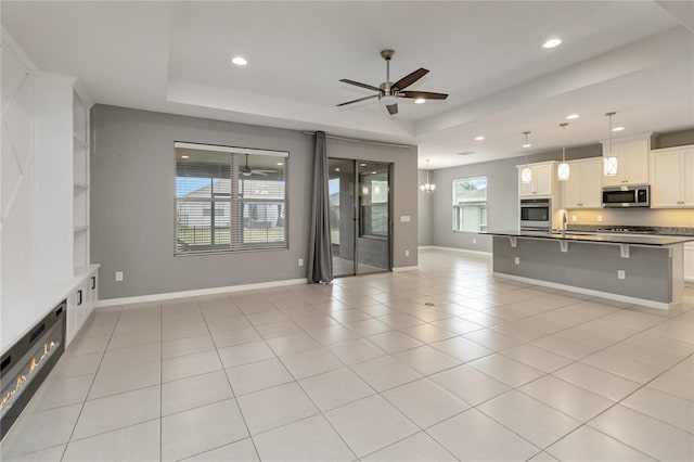 unfurnished living room featuring recessed lighting, a raised ceiling, and light tile patterned flooring