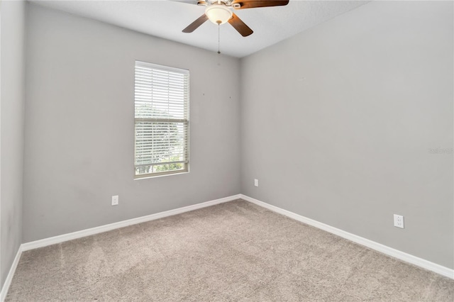 carpeted spare room with a ceiling fan and baseboards