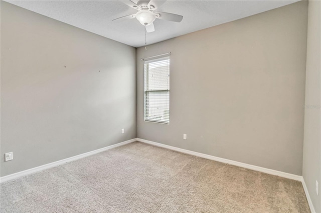 spare room featuring light colored carpet, ceiling fan, a textured ceiling, and baseboards