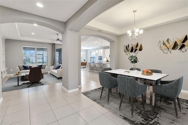 dining space featuring light tile patterned floors, baseboards, arched walkways, and a tray ceiling