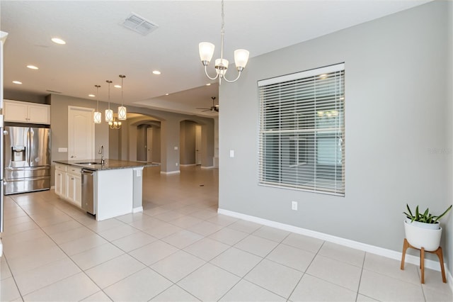 kitchen featuring visible vents, arched walkways, open floor plan, stainless steel appliances, and a sink