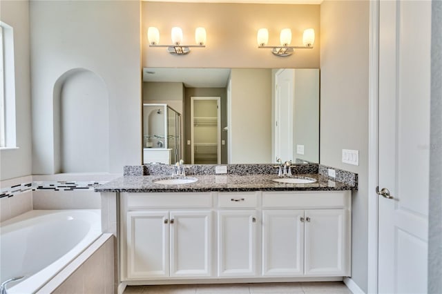 full bath with a bath, a shower stall, double vanity, and a sink