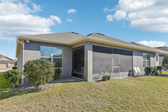 rear view of property featuring a sunroom, roof with shingles, a lawn, and stucco siding