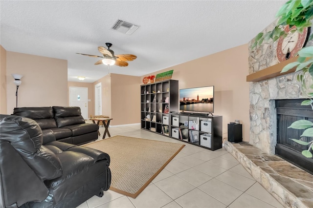 tiled living room with a fireplace, ceiling fan, and a textured ceiling