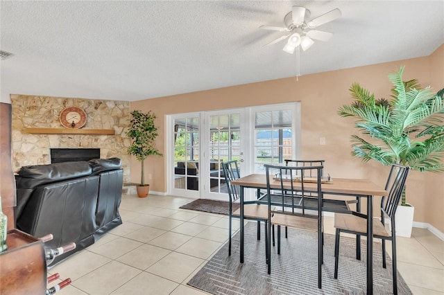 dining space with a fireplace, a textured ceiling, ceiling fan, and light tile patterned floors