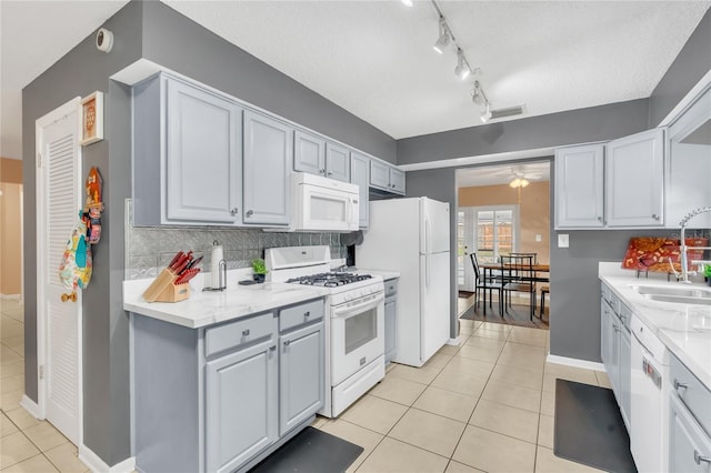 kitchen with white appliances, light tile patterned floors, backsplash, ceiling fan, and sink