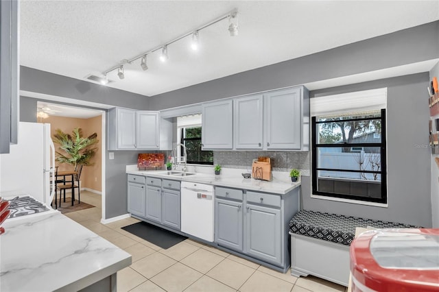 kitchen featuring white appliances, light stone countertops, gray cabinetry, and sink