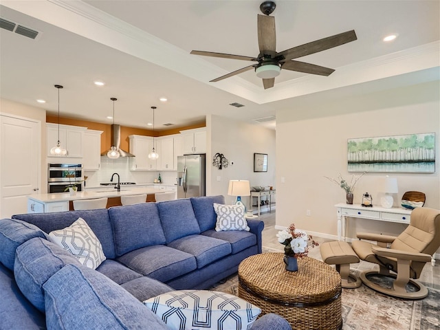 living room featuring a tray ceiling, crown molding, and ceiling fan