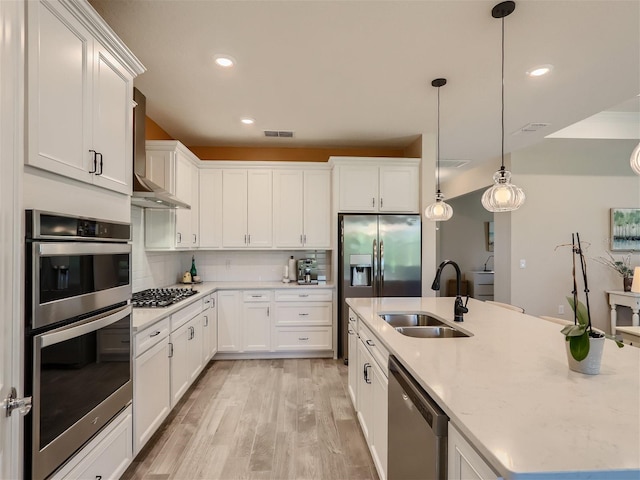 kitchen featuring stainless steel appliances, sink, white cabinets, and wall chimney exhaust hood