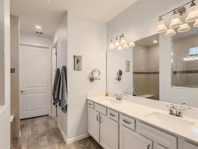 bathroom featuring hardwood / wood-style flooring, tiled shower, and vanity