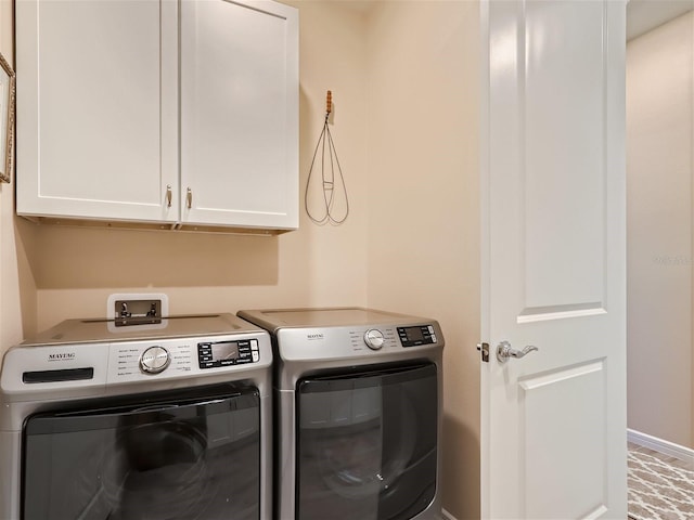 clothes washing area featuring cabinets and separate washer and dryer