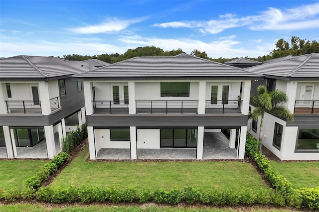 back of house with a yard, a balcony, a patio, and french doors