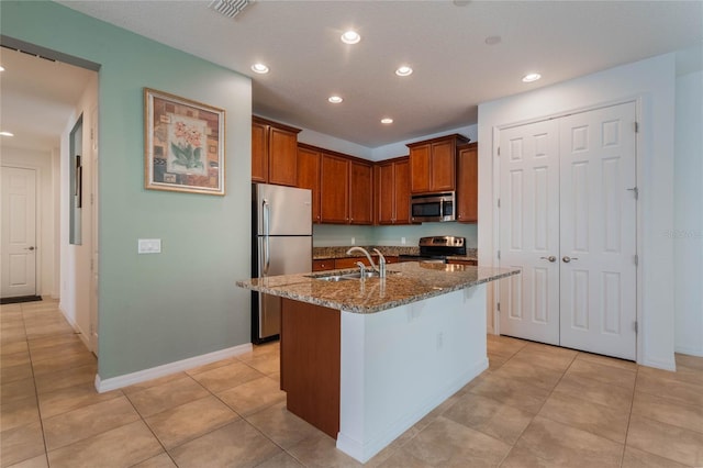 kitchen with dark stone counters, a kitchen breakfast bar, sink, an island with sink, and appliances with stainless steel finishes