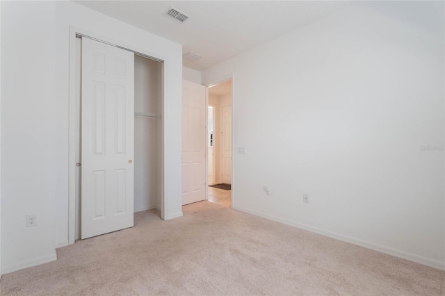 unfurnished bedroom with a closet and light colored carpet