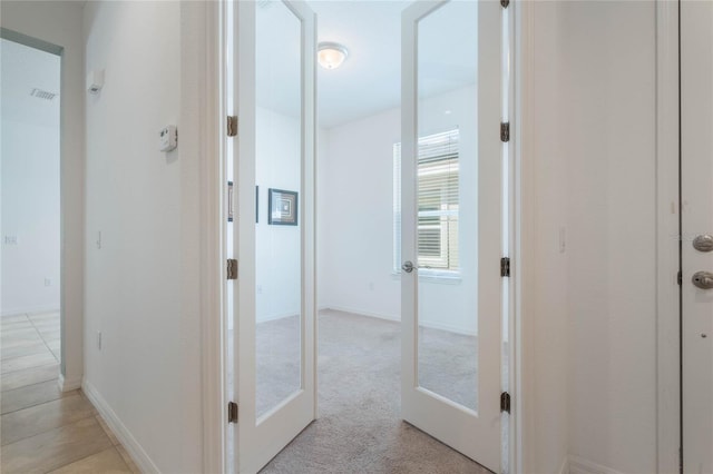 corridor with light carpet and french doors