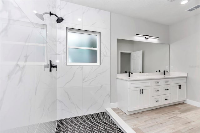 bathroom featuring hardwood / wood-style flooring, vanity, and a tile shower