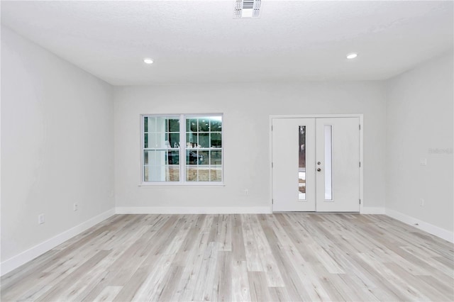 spare room with light hardwood / wood-style floors and a textured ceiling