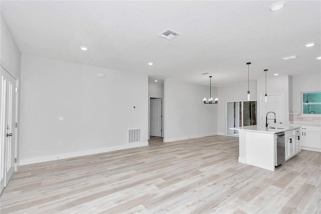 kitchen with a kitchen island with sink, white cabinets, sink, stainless steel dishwasher, and decorative light fixtures