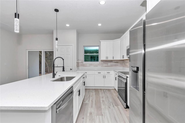 kitchen featuring white cabinets, stainless steel appliances, hanging light fixtures, and sink