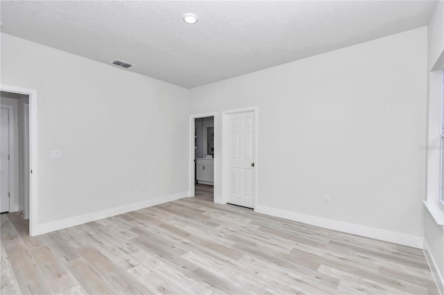 unfurnished room featuring light hardwood / wood-style floors and a textured ceiling