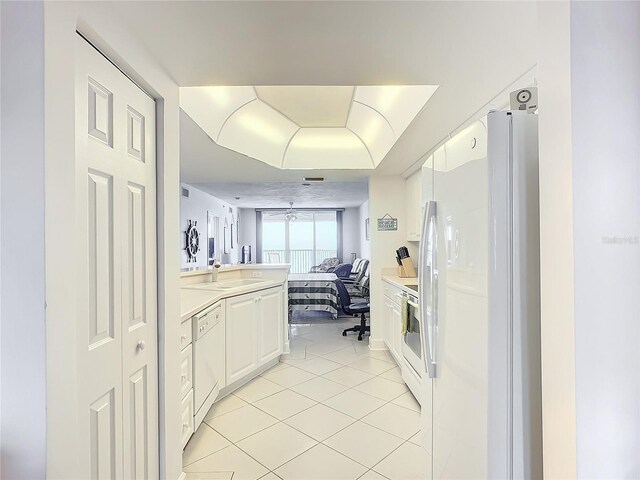 kitchen with white appliances, white cabinetry, sink, kitchen peninsula, and light tile patterned flooring