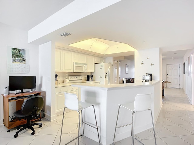 kitchen with a breakfast bar area, light tile patterned floors, a center island, and white appliances