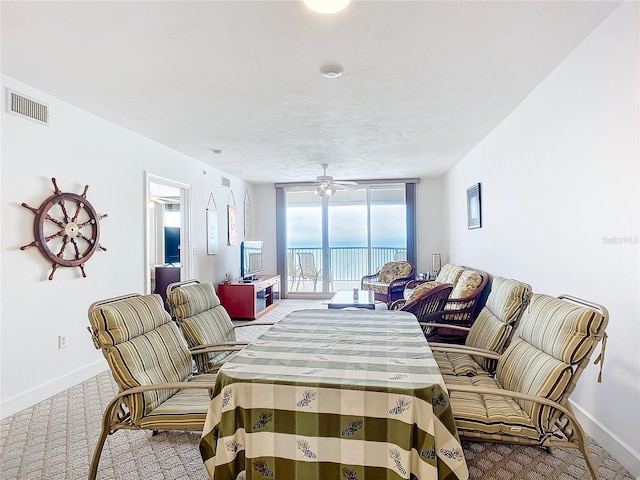 dining space with light carpet, ceiling fan, and a wall of windows