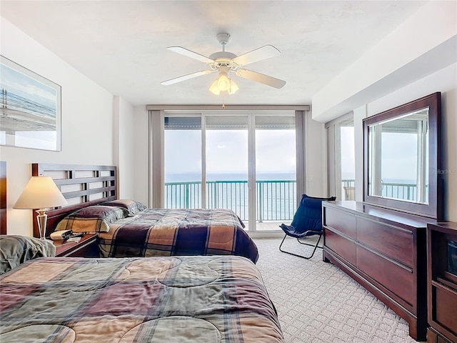 carpeted bedroom featuring a water view, access to outside, and ceiling fan