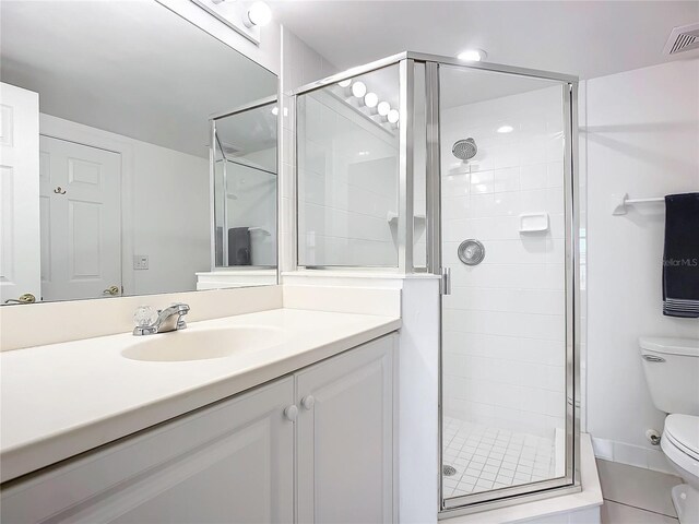 bathroom featuring toilet, tile patterned floors, walk in shower, and vanity