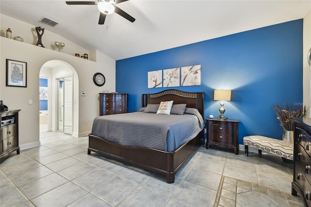 tiled bedroom featuring ceiling fan, ensuite bathroom, and vaulted ceiling