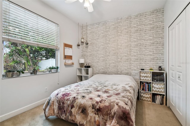 carpeted bedroom with brick wall, ceiling fan, and a closet