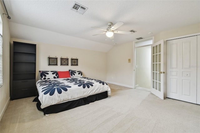 carpeted bedroom with ceiling fan, a closet, lofted ceiling, and a textured ceiling