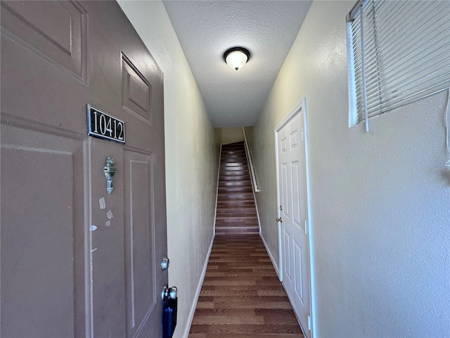 hall featuring dark wood-type flooring and a textured ceiling