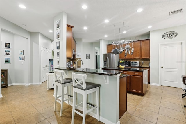 kitchen featuring light tile patterned floors, a kitchen breakfast bar, stainless steel fridge with ice dispenser, decorative backsplash, and a kitchen island