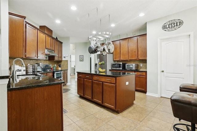 kitchen featuring a center island, sink, appliances with stainless steel finishes, and dark stone counters