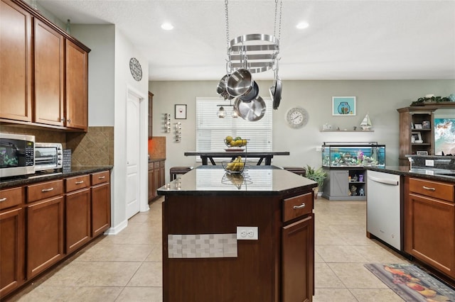 kitchen featuring dishwashing machine, a center island, tasteful backsplash, and light tile patterned flooring