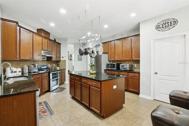 kitchen with sink, dark stone countertops, light tile patterned floors, a kitchen island, and stainless steel appliances