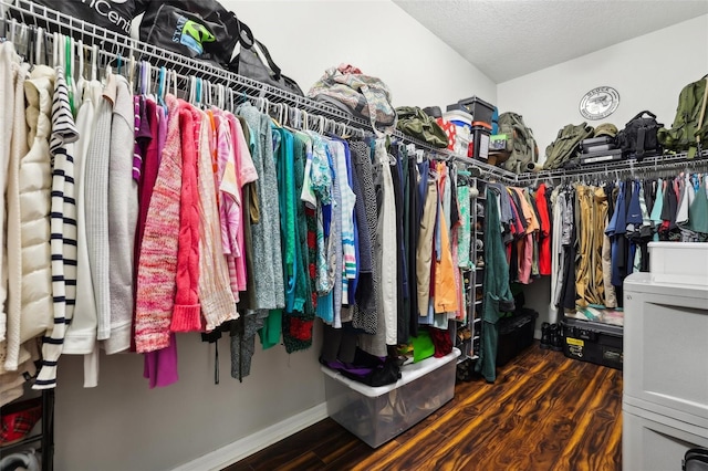 walk in closet with dark wood-type flooring and washer / dryer