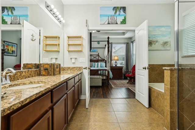 bathroom with tile patterned floors, tiled tub, and vanity